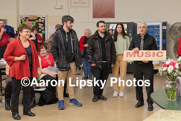 Mark Polifrone holds sign as, standing from far left, his wife Kathleen, his twin sons Kevin and Matthew, and his daughter Margaret look on at reception after his final Holiday Concert at MRHS Saturda